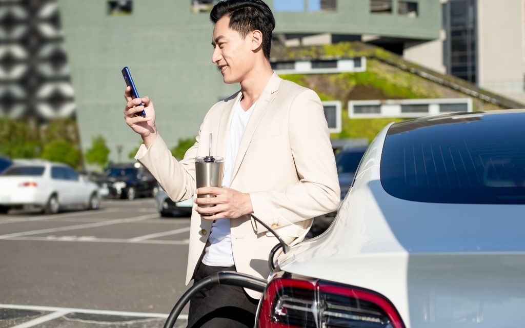 man charging a tesla holding a smartphone Frank Mobile Australia