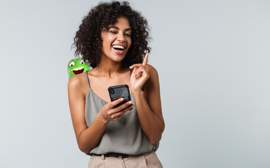 The Mobile Monster character peeking over a happy woman's shoulder who is holding a smartphone