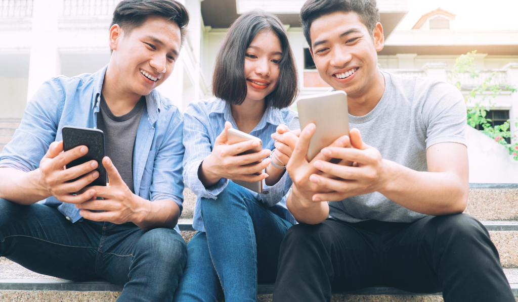 Three Friends Sitting On A Stoop Holding Smartphone and Engaging With Each Other