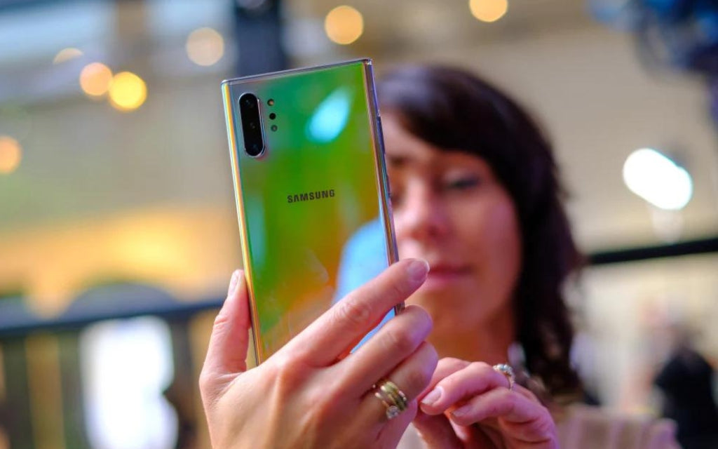 Brunette woman wearing gold rings holding a Samsung Galaxy Smartphone