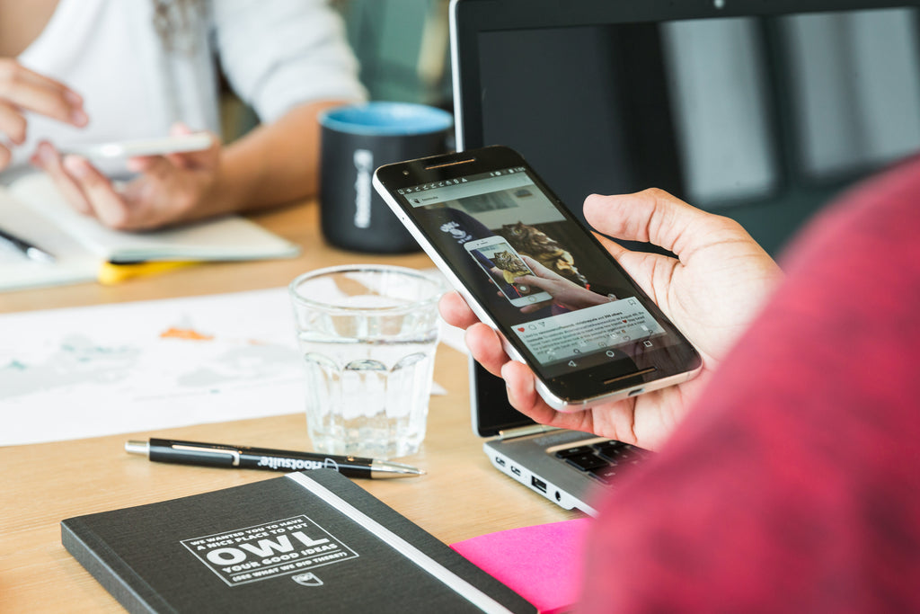 hand holding smartphone in office meeting