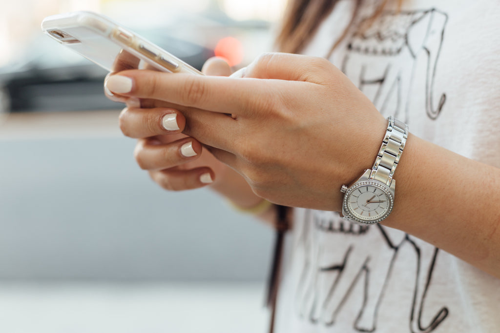 feminine hands holding an iphone wearing a silver watch