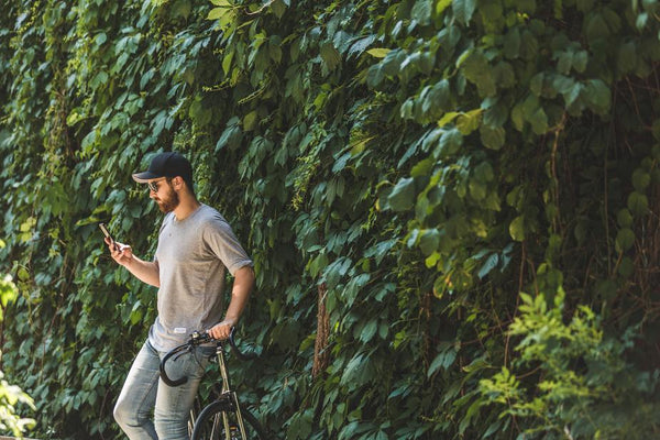 stylish casual guy leaning against a bicycle texting outside Frank Mobile