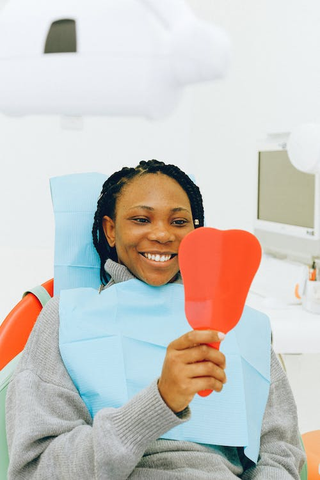 A Woman Looking at her Teeth in a Handheld Mirror After a Dental Cleaning