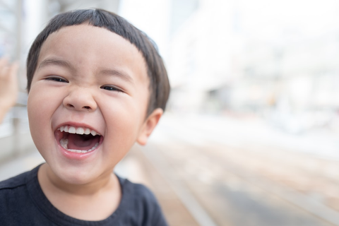 A Child Laughing, Showing Off Teeth Freshly Brushed with an Electric Flosser