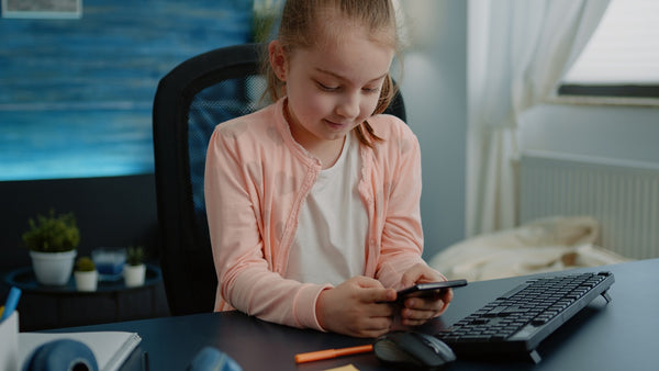 little girl looking at her phone while on her study desk