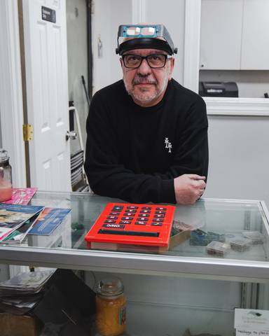 Master jeweler crafting a delicate piece in his workshop. Surrounding him are tools of the trade.