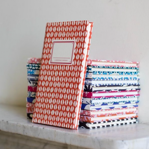 Stack of fabric pattern notebooks, in brightly dyed colours. By Cambridge Imprint