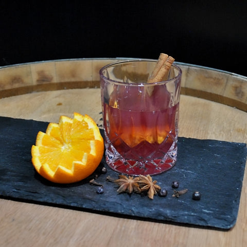 Mulled Wine Gin Hot Toddy Recipe. Winter gin cocktail, served with cinnamon quill, on slate with orange close and star anises garnish. Newy Distillery