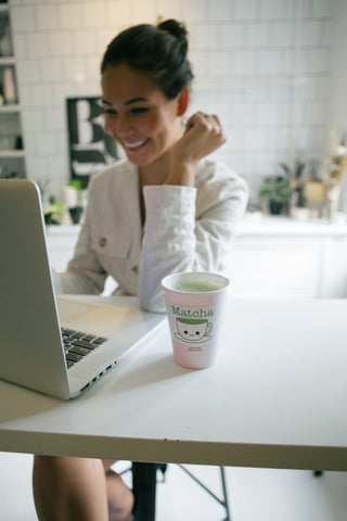 Woman working on her laptop with matcha on her desk