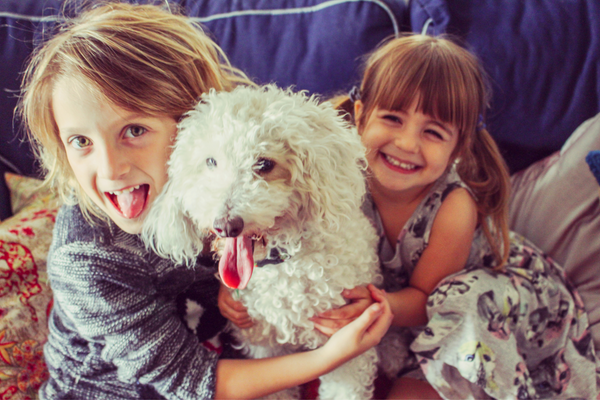 two girls hugging a white dog