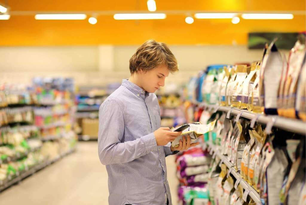 young man reading dog food label in store