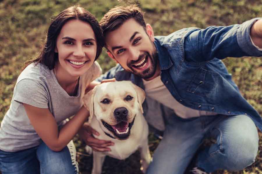 millennial couple taking selfie with white dog