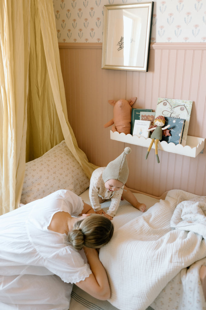 mom and baby play on toddler bed with canopy