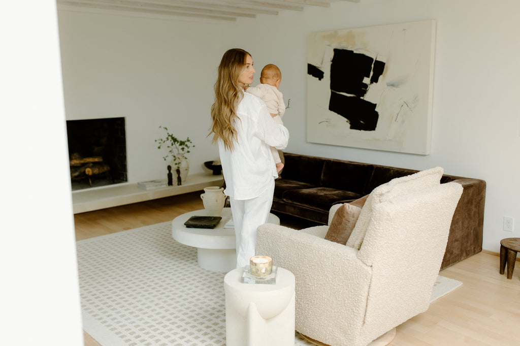 woman standing with baby next to a Flynn recliner and white side tables