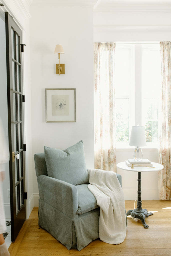 glider with toddler blanket draped across next to crystal lamp