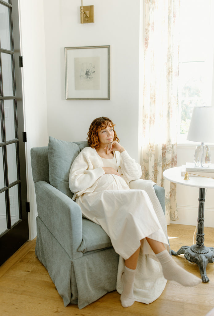 woman in Oilo Zoey glider next to a crystal table lamp