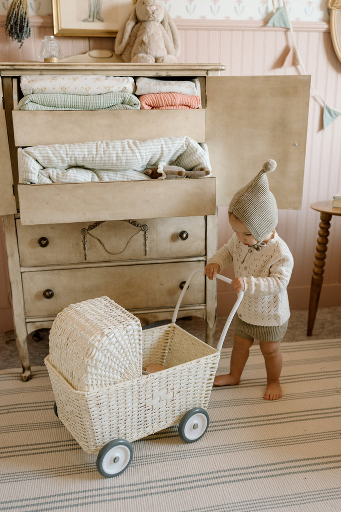 toddler pushing pram on stripped rug