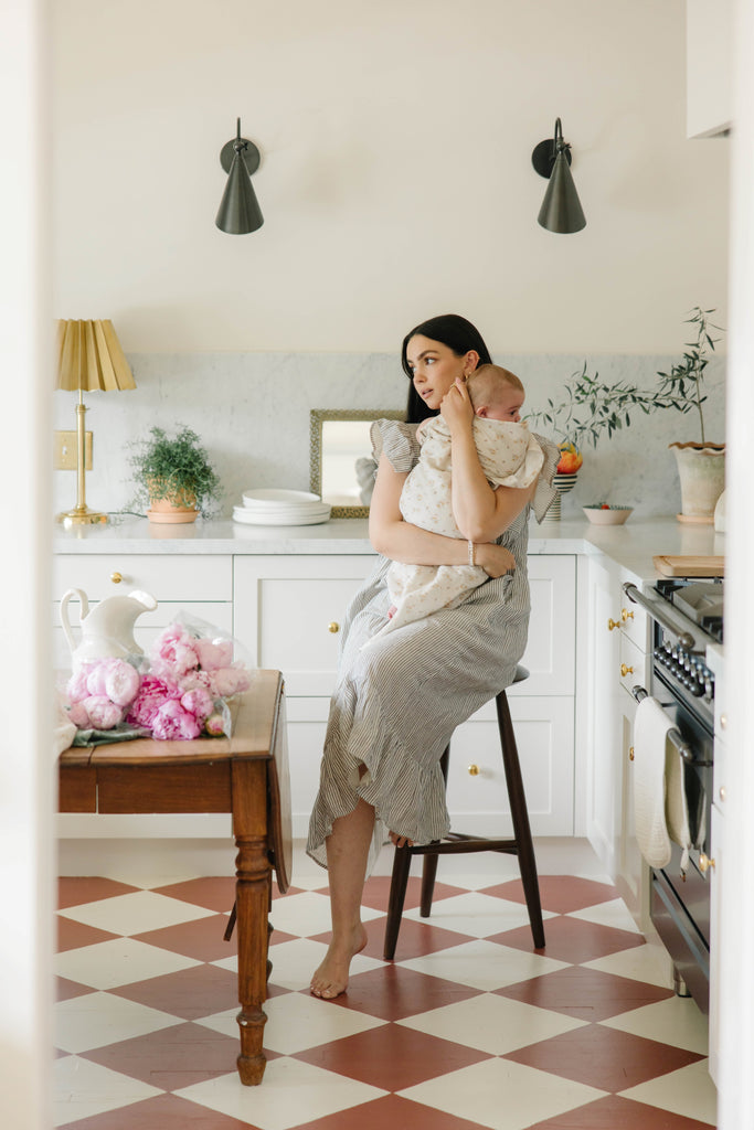 eclectic style home kitchen with woman sitting on stool holding baby