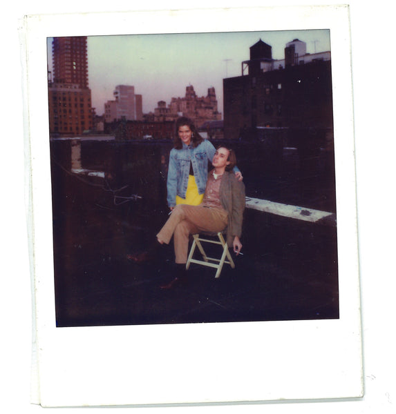 Ann and Sid on the rooftop of Sid's first apartment in NYC. There's a great city view in the background, and they are smiling.