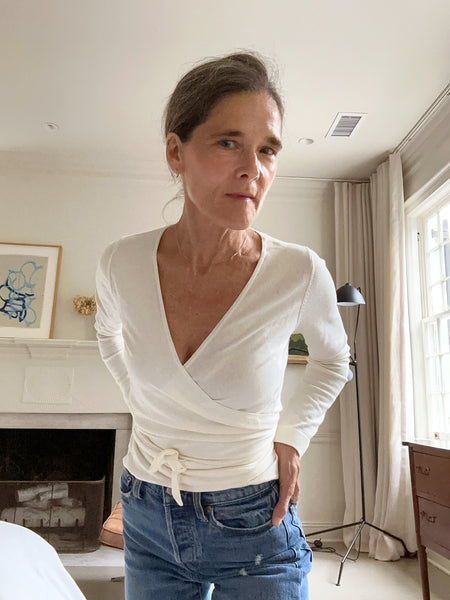 Ann at home in an ivory cache-cœur wrap sweater and mid-wash blue denim.