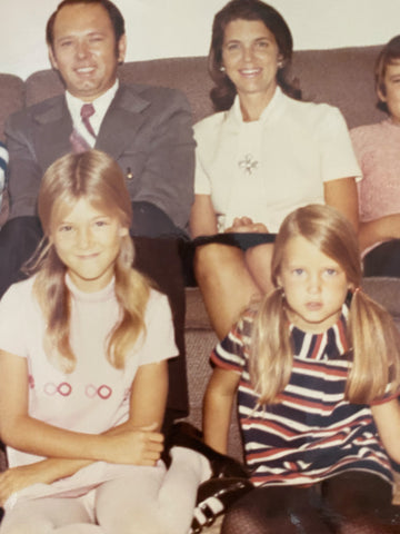 A family photo of Ann's father, mother, Ann, and her sister. Ann is wearing the mentioned YSL-inspired homemade dress with pink and white loops across the bodice. The dress has a mock-neck and short sleeves. Ann's sister looks equally Yves-y with a mod striped shift dress.