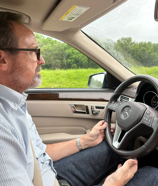 Sid behind the wheel in a blue university striped oxford button-down and a pair of dark indigo non-selvedge jeans.