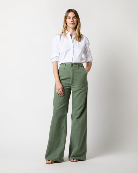 Premium Photo | Woman in white shirt and green pants with sunglasses in  hand walking down the alley of the park.