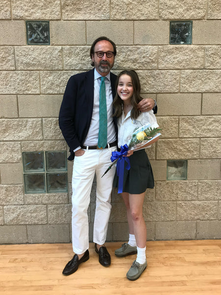 Sid and his daughter, Pauline at a school event. Sid is wearing a textured coat, a blue green tie with a little texture to it, a pale blue dress shirt, natural rinse denim, and a chocolate leather pair of tassel loafers.