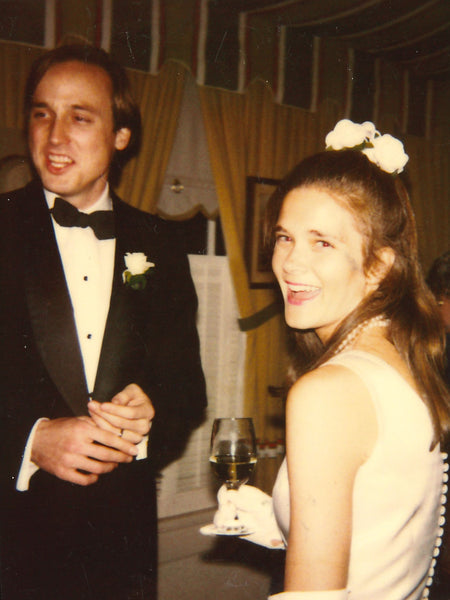 Sid and Ann on their wedding day 35 years ago. Sid is in a shawl collar tuxedo, and Ann is in a wedding dress and gloves with flowers in her hair.