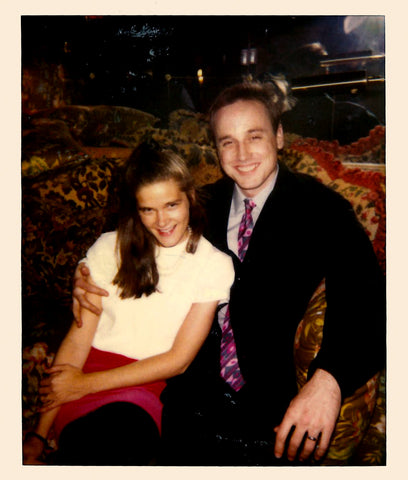 Ann and Sid at a cocktail party in NYC in the late 80s. Ann is in a white top, a pink silk skirt, and tights, and Sid is in a dark sport coat, dark trousers, a light-colored dress shirt, and a pink and purple paisley silk tie.