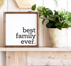 wood framed square sign with 'best family ever' painted in black on a white background.