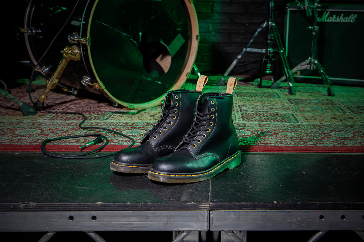 A pair of Dr. Martens 1460 in Black on the a stage with a drum kit in the background.