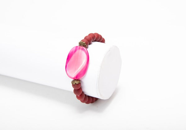 A bracelet with an epoxy resin ornament featuring a pinkish-red resin dye tint.