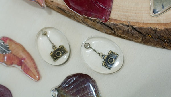 Two clear resin pendants with embedded charms.