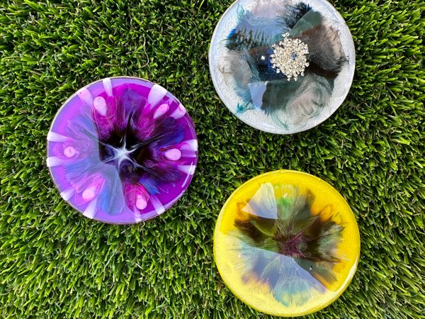 Three resin coasters made using epoxy resin, resin molds, and alcohol inks.