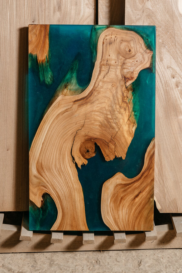 A wooden epoxy serving tray standing vertically. The epoxy in it has been tinted blue.