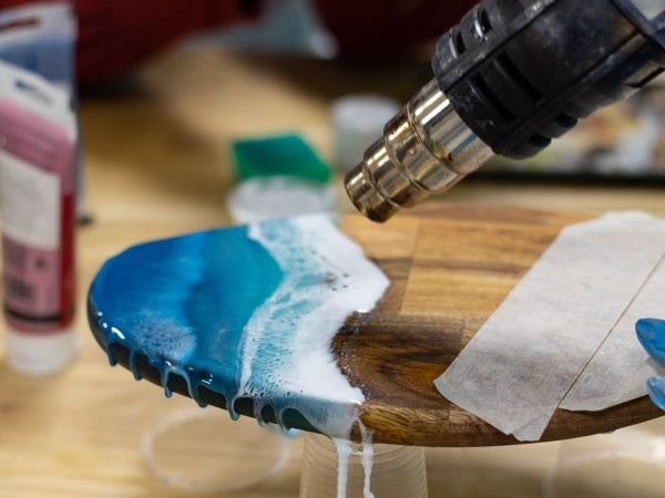 A heat gun being used to make "waves" with blue-pigmented epoxy resin.