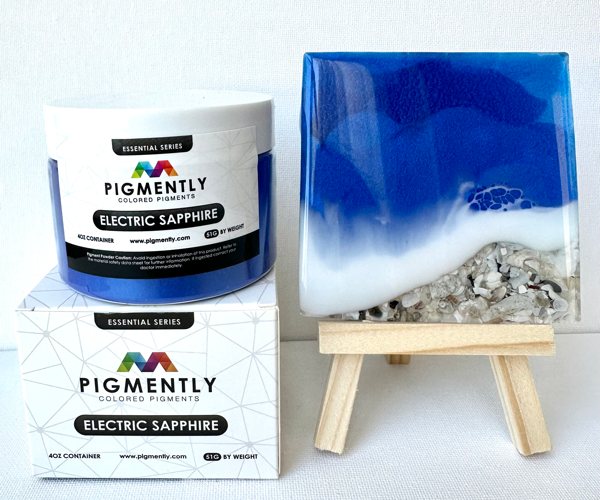 An epoxy resin art piece made to look like blue ocean water flowing over seashells. The pigment used was Pigmently's Electric Sapphire Mica Powder.