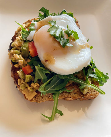 Avocado toast on wheat bread with poached egg, parmagiano tapenade, olives