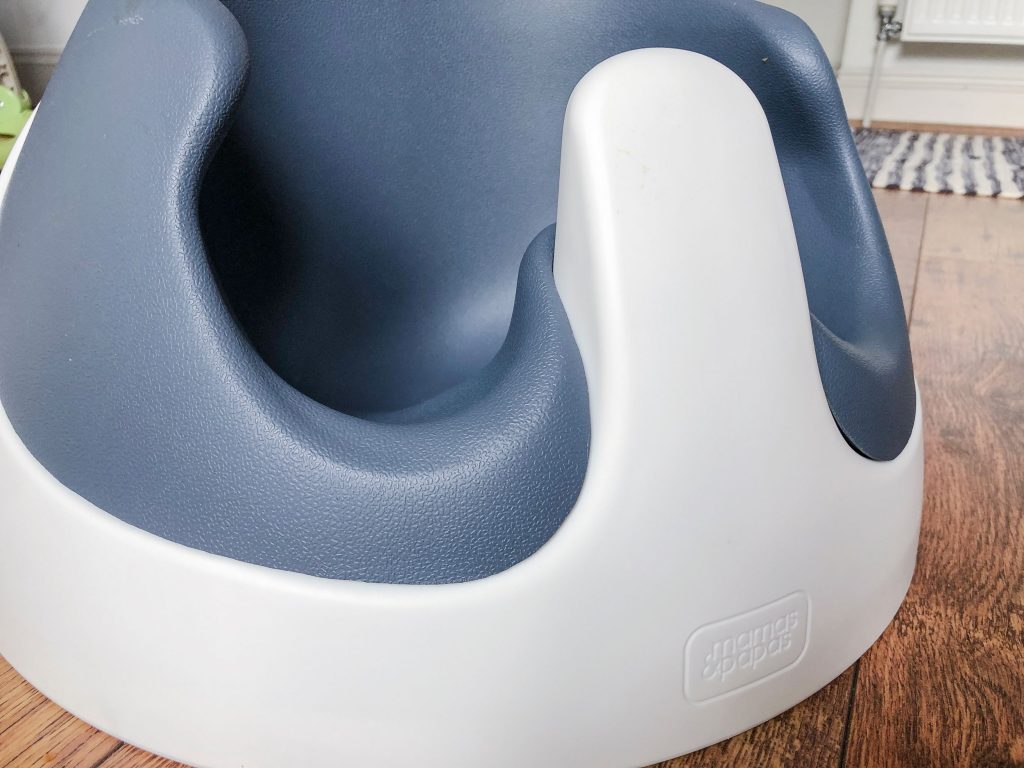 A close up of the Baby Snug booster seat with a navy coloured soft insert and white formed shape.