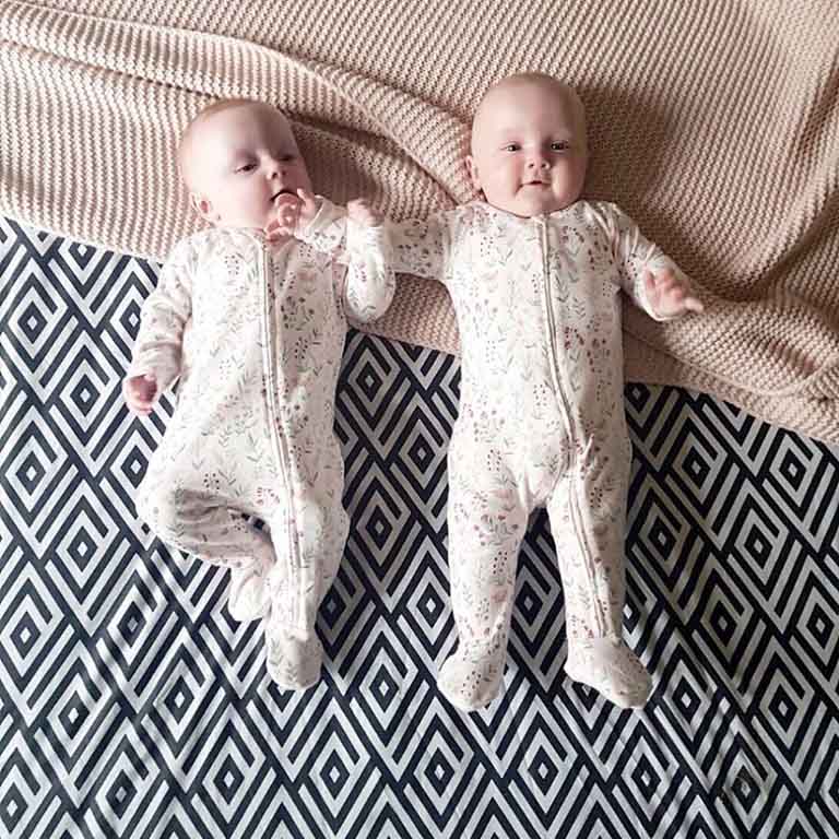 Twin girls lying on a blanket