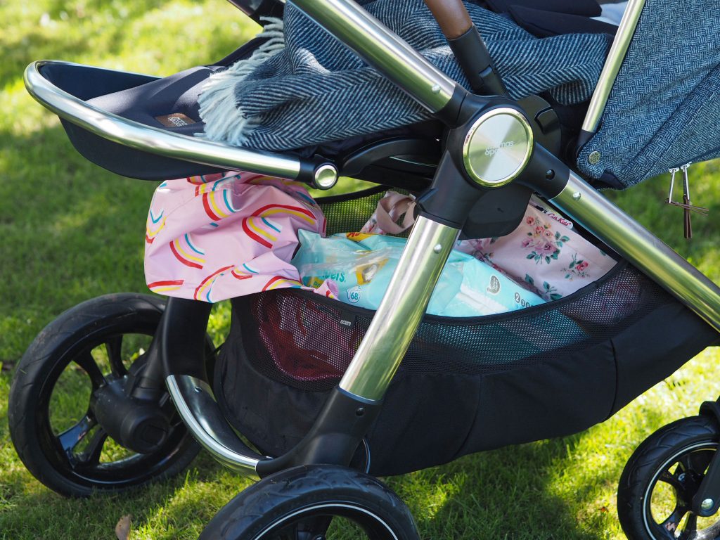 Close up of the Ocarro moon pushchair and the large shopping basket under the seat. It is full of coats and clothes and other accessories.
