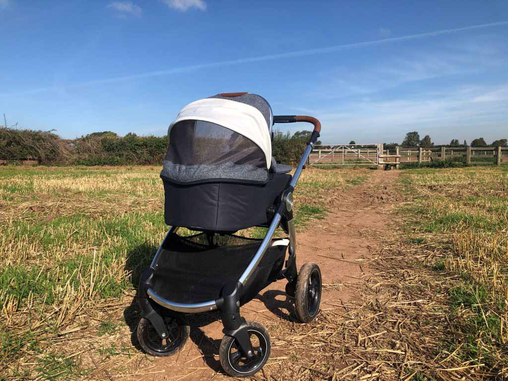 Image of the Ocarro Moon pushchair on a dirt track in the middle of a field. 