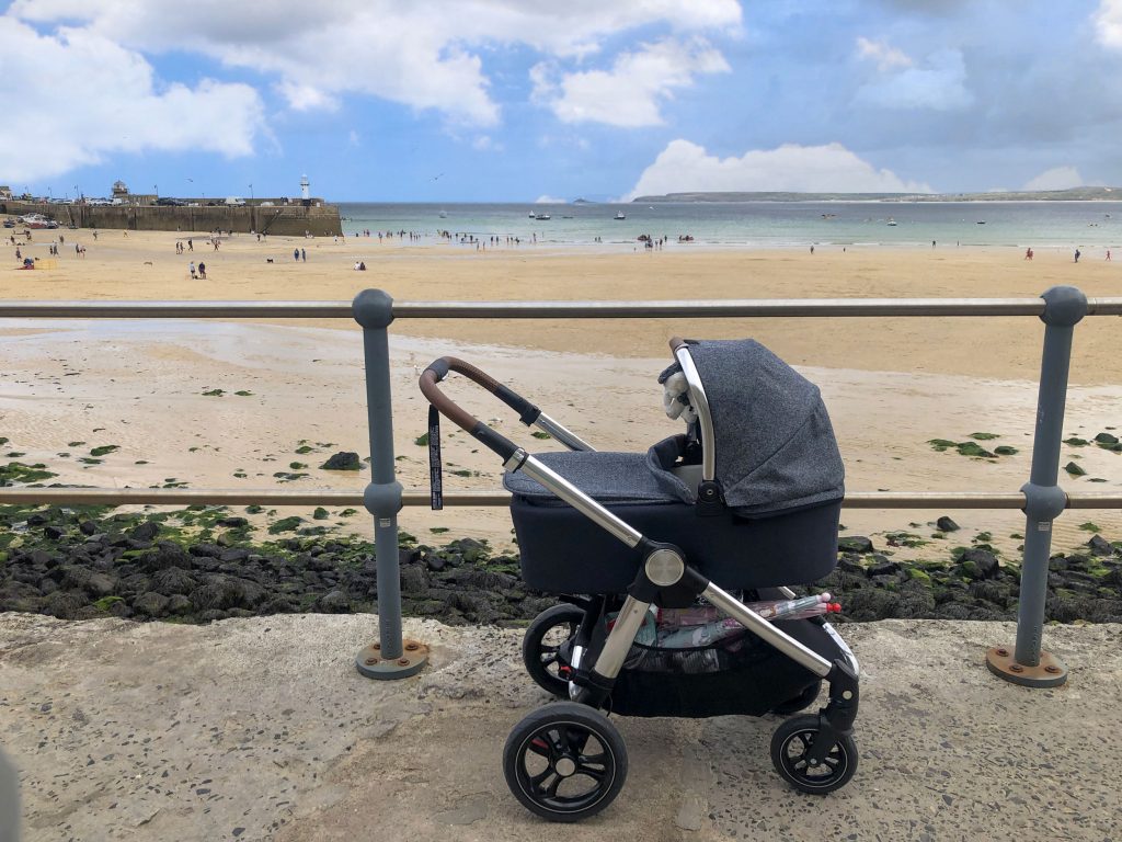 Image of the Ocarro Moon pushchair on a pavement overlooking a sunny beach.