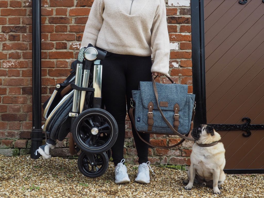 Image of Harley holding the Ocarro pushchair, which is folded up into a compact size, and a matching changing bag.