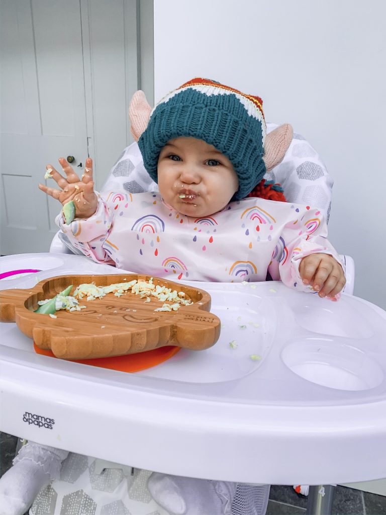 Baby Luna eating some food while sat in the highchair. 