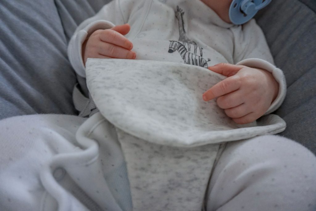 A close up of baby Theo asleep in the Apollo cradle. We can see the soft fabric harness that keeps him in place.