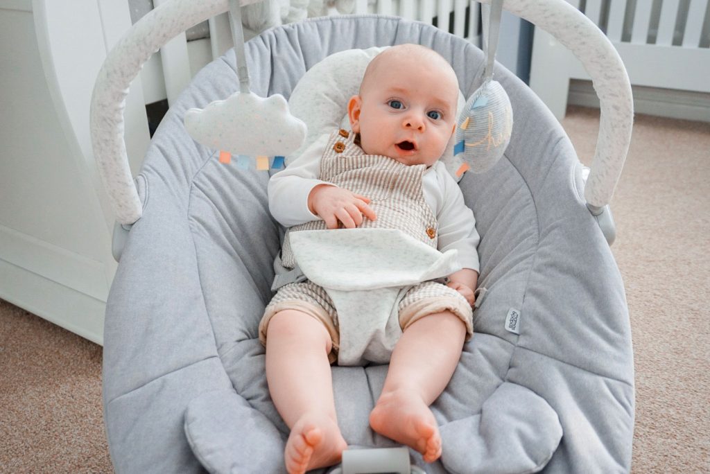 Another image of baby Theo sat in his Apollo cradle, playing. He is looking at the hanging toys.