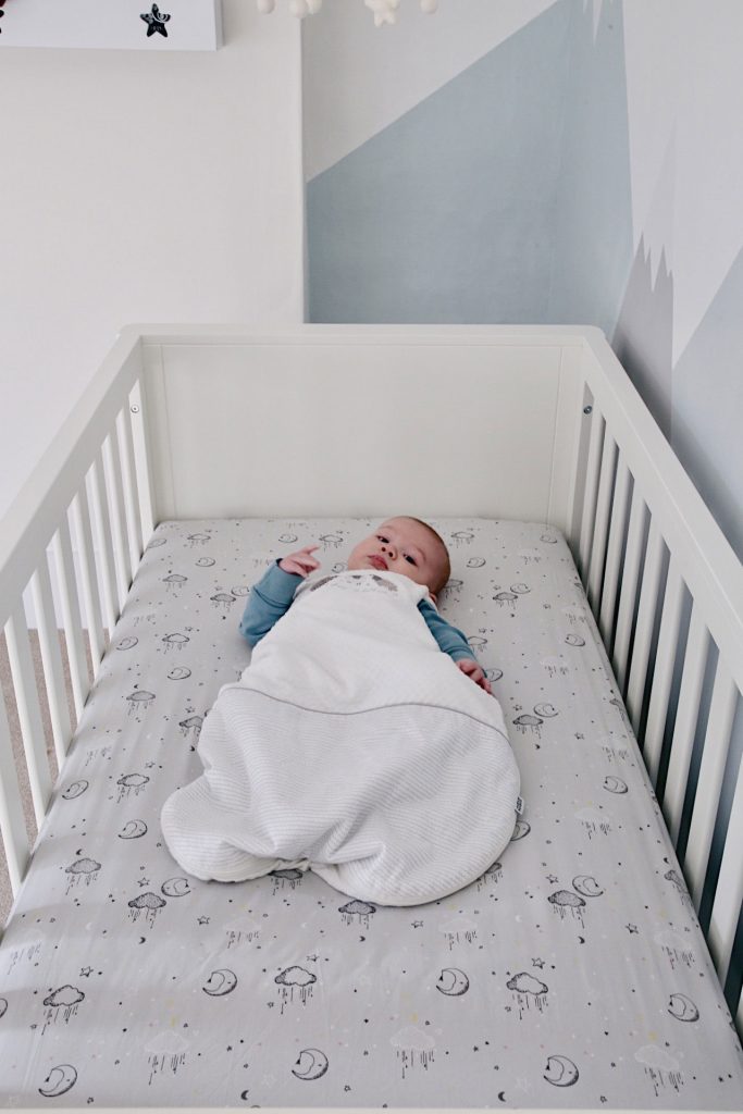 Image of Baby Gabriel in a sleep bag in the cot bed with the Dream Upon a Cloud bedding.